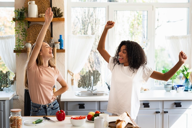 Due amiche che ballano mentre cucinano in cucina