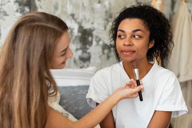 Two female friends doing make-up on each other