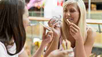 Foto gratuita due amiche che godono di hamburger e patatine fritte al ristorante