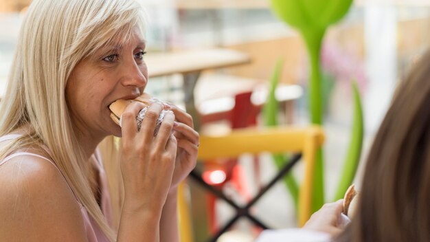 Two female friends enjoying burgers at restaurant together