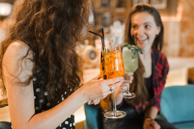 Две подружки наслаждаются коктейлем в баре
