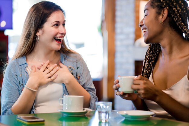 Two female friends enjoying a cup of coffee together.