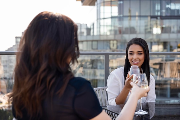 Two female friends enjoying some wine on a rooftop terrace