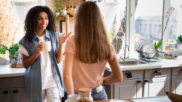two female friends having a conversation in the kitchen