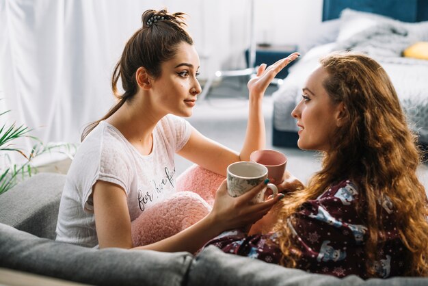 Two female friends having conversation while drinking coffee