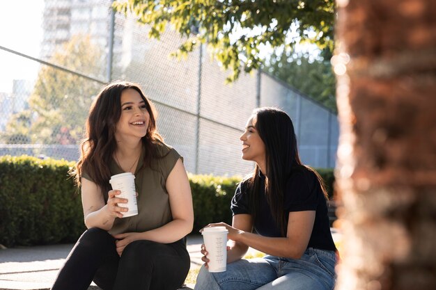 Two female friends having a cup of coffee together at the park