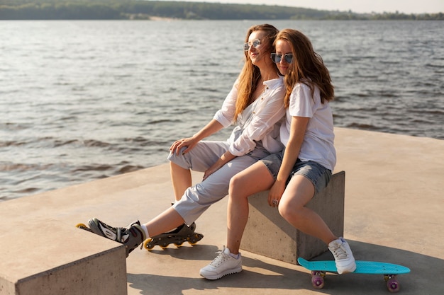 Two female friends having fun by the lake with roller blades