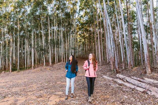 Two female friends hiking in front of tall trees