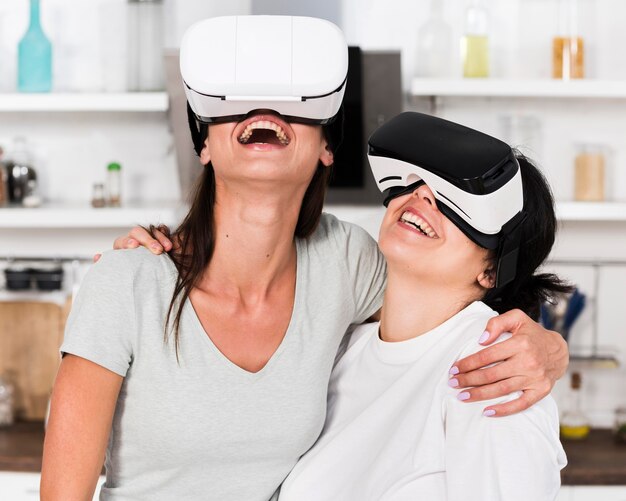 Two female friends at home having fun with virtual reality headset