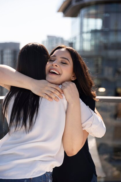 Two female friends hugging after seeing each other at a rooftop terrace