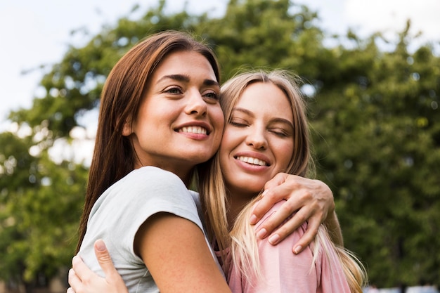 Two female friends hugging each other outdoors