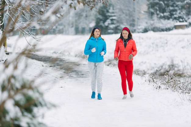 Two female friends jogging in the winter
