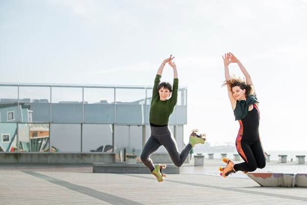 Two female friends jumping with roller skates outdoors