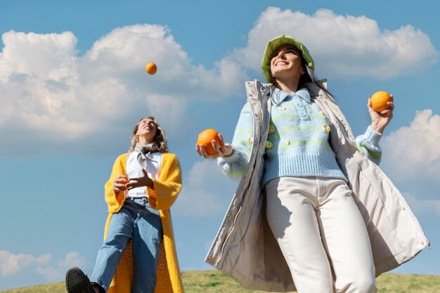 Two female friends playing with oranges in an outdoor field