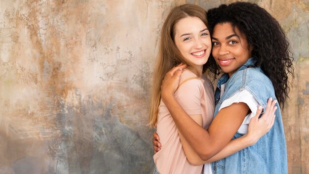 Two female friends posing while hugging with copy space