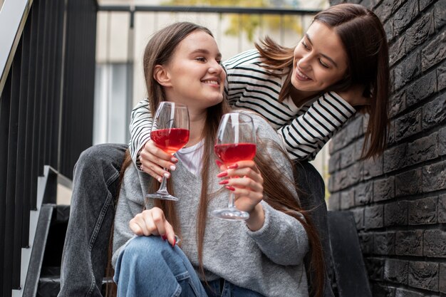 Two female friends smiling while holding glasses of wine