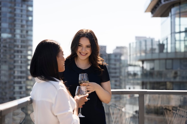 Two female friends spending time together and drinking wine on a rooftop terrace