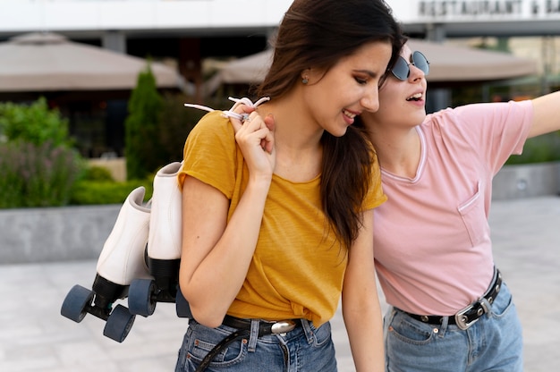 Two female friends spending time together outdoors and carrying roller skates