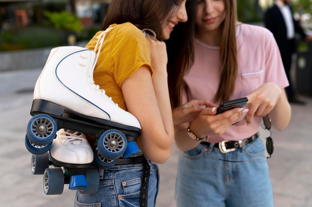 Two female friends spending time together outdoors and carrying roller skates