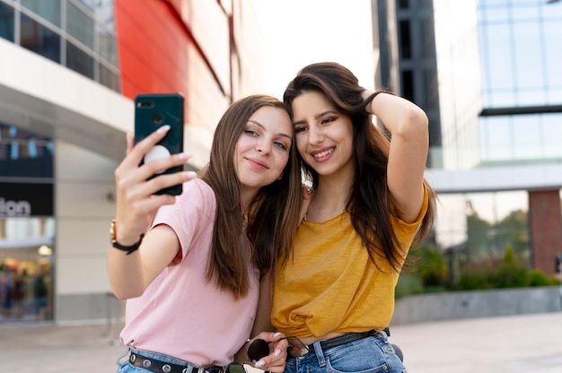 Two female friends spending time together outdoors and taking selfie