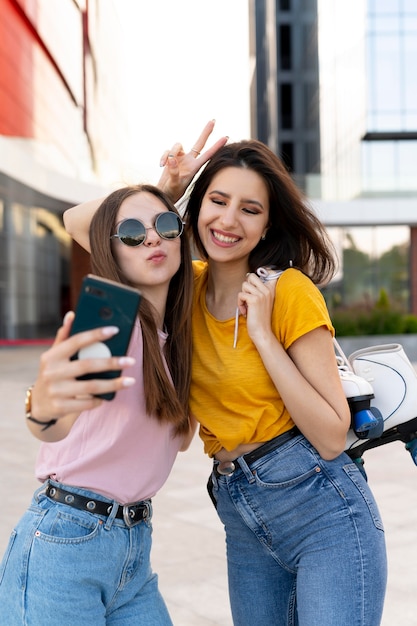 Two female friends spending time together outdoors and taking selfie