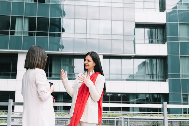 Two female friends talking in front of building