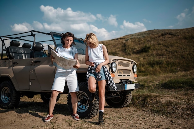 Two female friends traveling by car and checking map