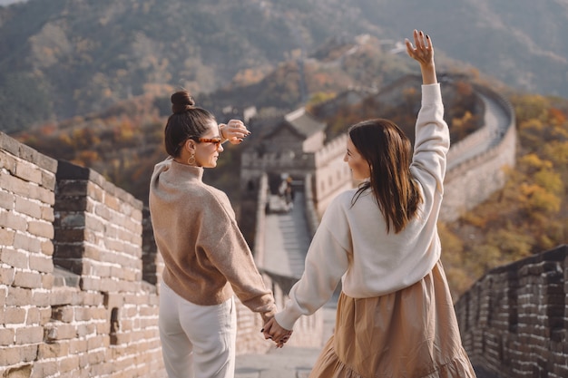 Free photo two female friends walking along the great wall of china near the beijing entarnce