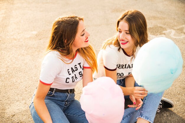 Two female friends with candy floss looking at each other
