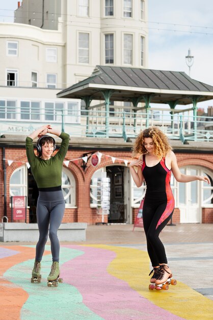 Two female friends with roller skates dancing outdoors