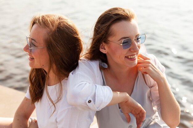 Two female friends with sunglasses having fun by the lake