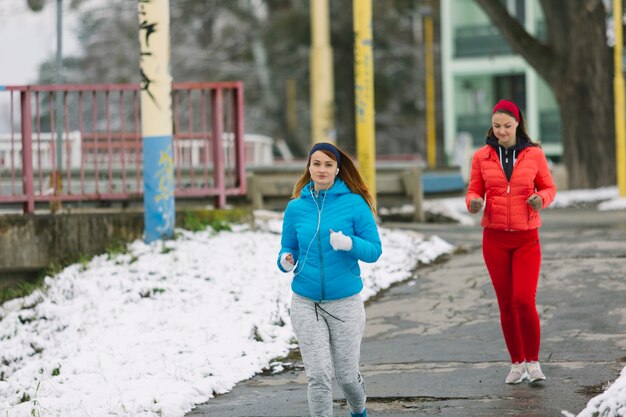 Две женские бегуны, бегущие по улице зимой