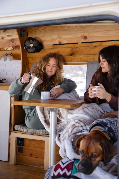 Two female lovers drinking coffee in a camper van during winter trip