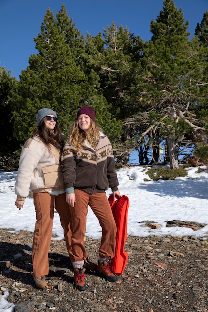 Бесплатное фото Две любовницы позируют вместе с санями во время зимней поездки