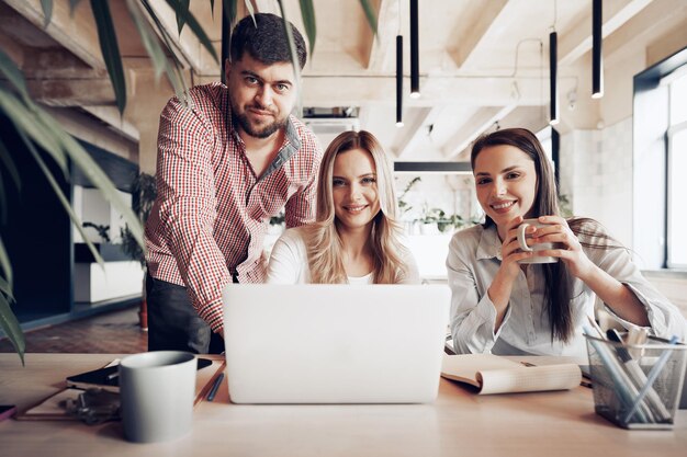 Two female and one male business partners looking at computer screen and discussing their project