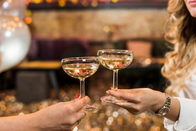 Two female's hand toasting whiskey at night club