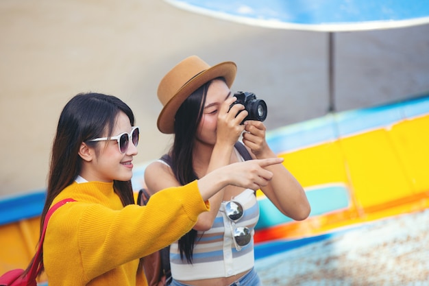 Two female tourists hold a map to find places.