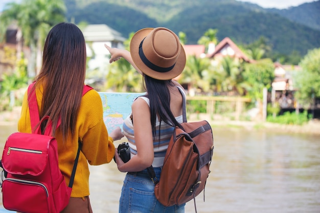 2人の女性観光客が場所を見つけるために地図を持っています。