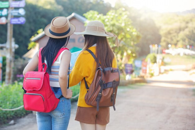 Two female tourists hold a map to find places.