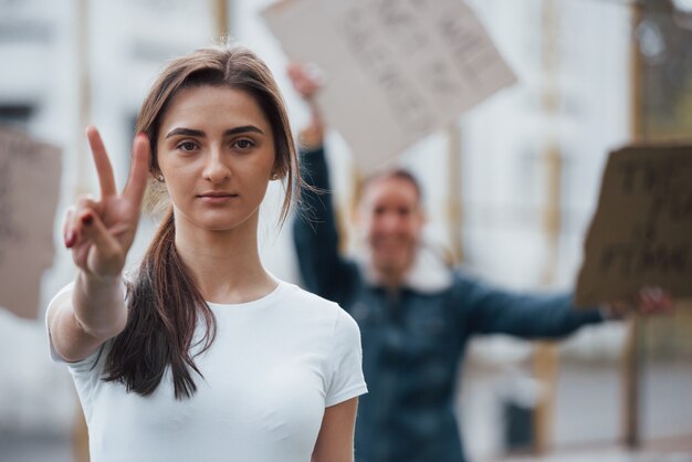 두 손가락 제스처. 페미니스트 여성 그룹이 야외에서 자신의 권리를 위해 항의