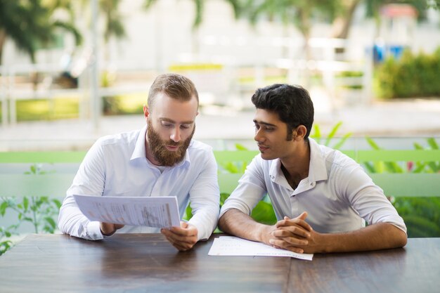 Two focused business men meeting and working in outdoor cafe