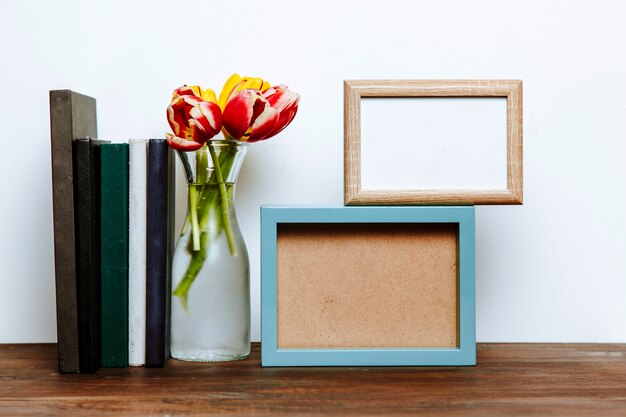 Two frames near vase and books