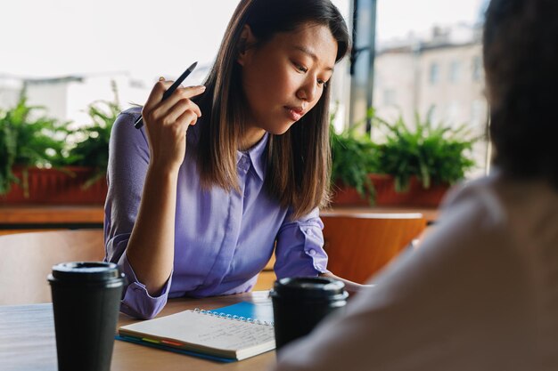 Two freelance women discussing project while drinking coffee