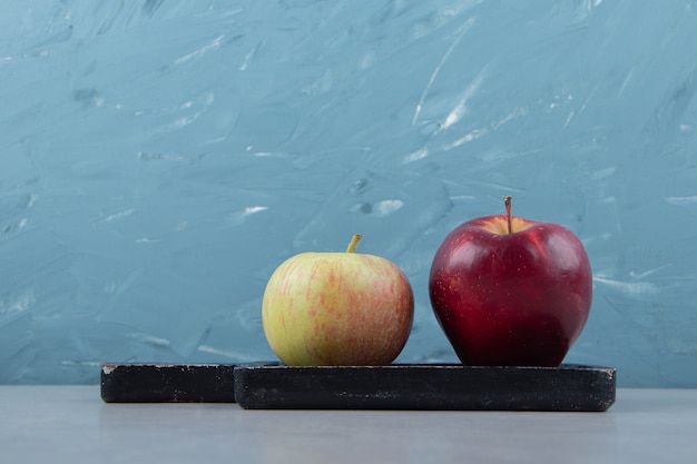 Free photo two fresh apples on black cutting board.