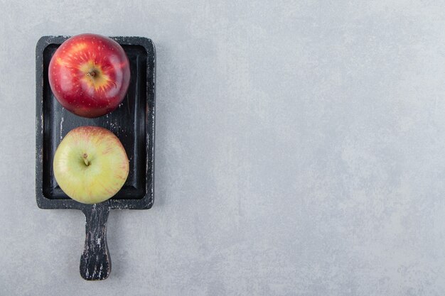 Two fresh apples on black cutting board
