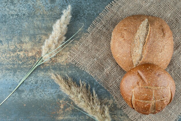 Two fresh brown bun with wheat on sackcloth 