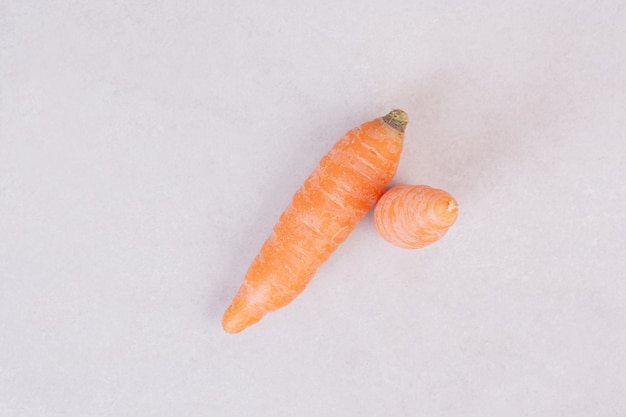 Two fresh carrots on white table.