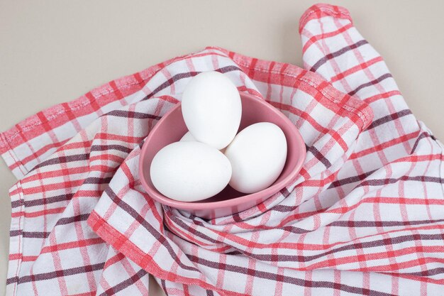 Two fresh chicken white eggs on tablecloth.