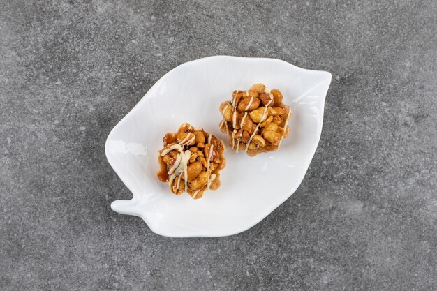 Два свежих печенья с арахисом на белой тарелке на серой поверхности