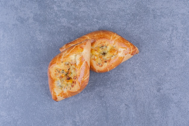 Two fresh delicious pastries on a gray surface